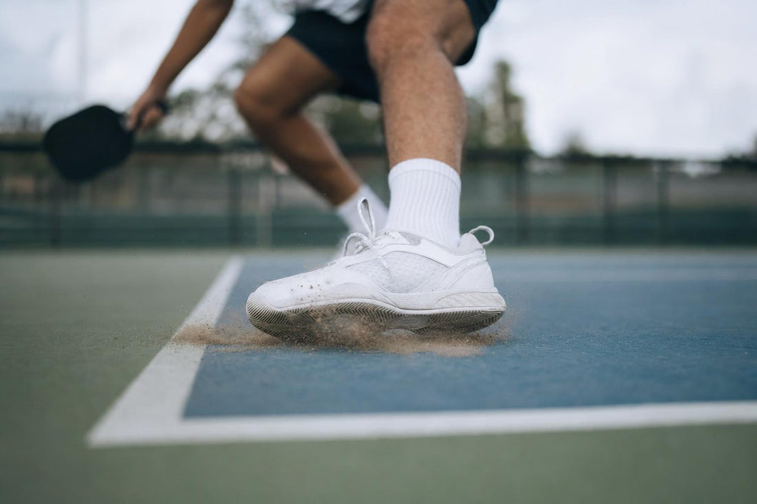 Primer plano de unas zapatillas frenando en seco sobre una pista de pickleball