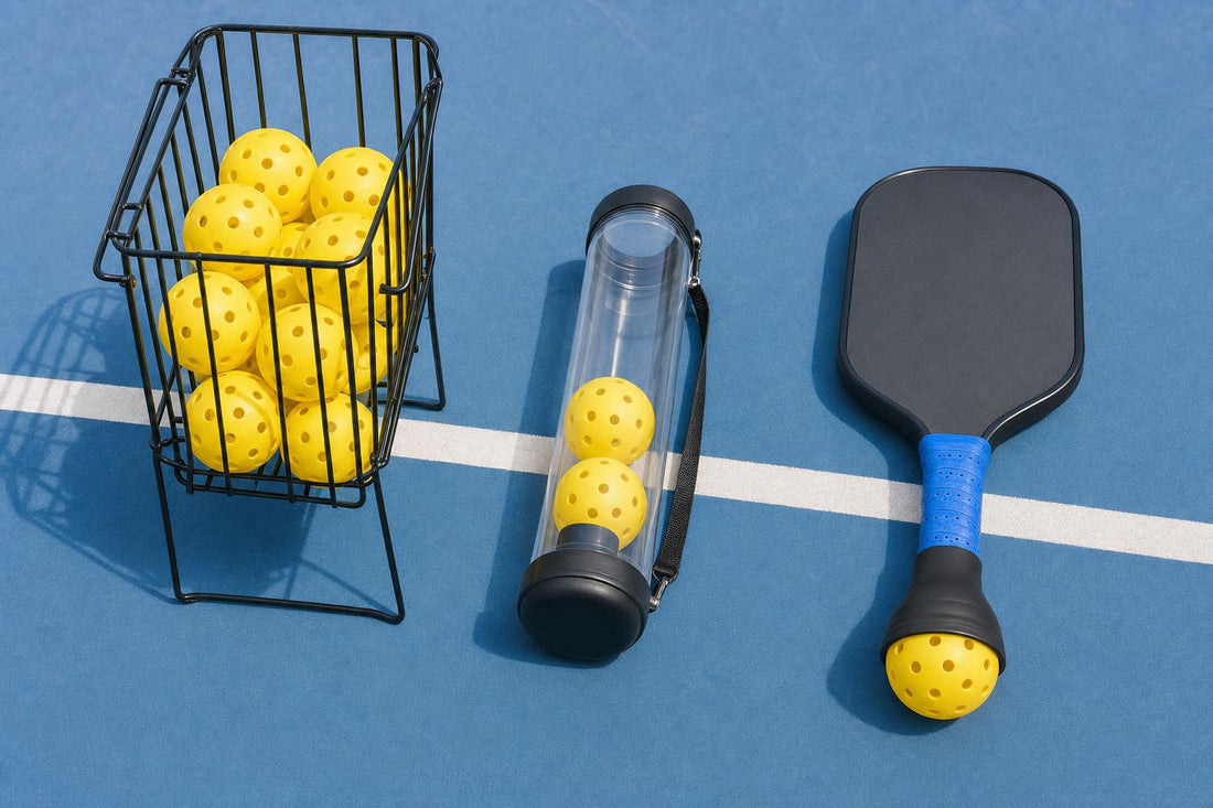 Three types of pickleball ball pickup tools on the court: basket with balls, clear tube and a paddle-handle pickup tool