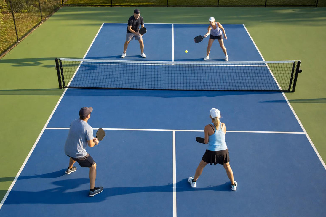 Partido de dobles de pickleball visto desde arriba, dos jugadores a cada lado de la red