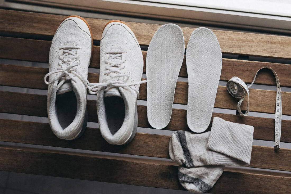 Zapatillas de pista con las plantillas fuera y una cinta métrica para medir la talla
