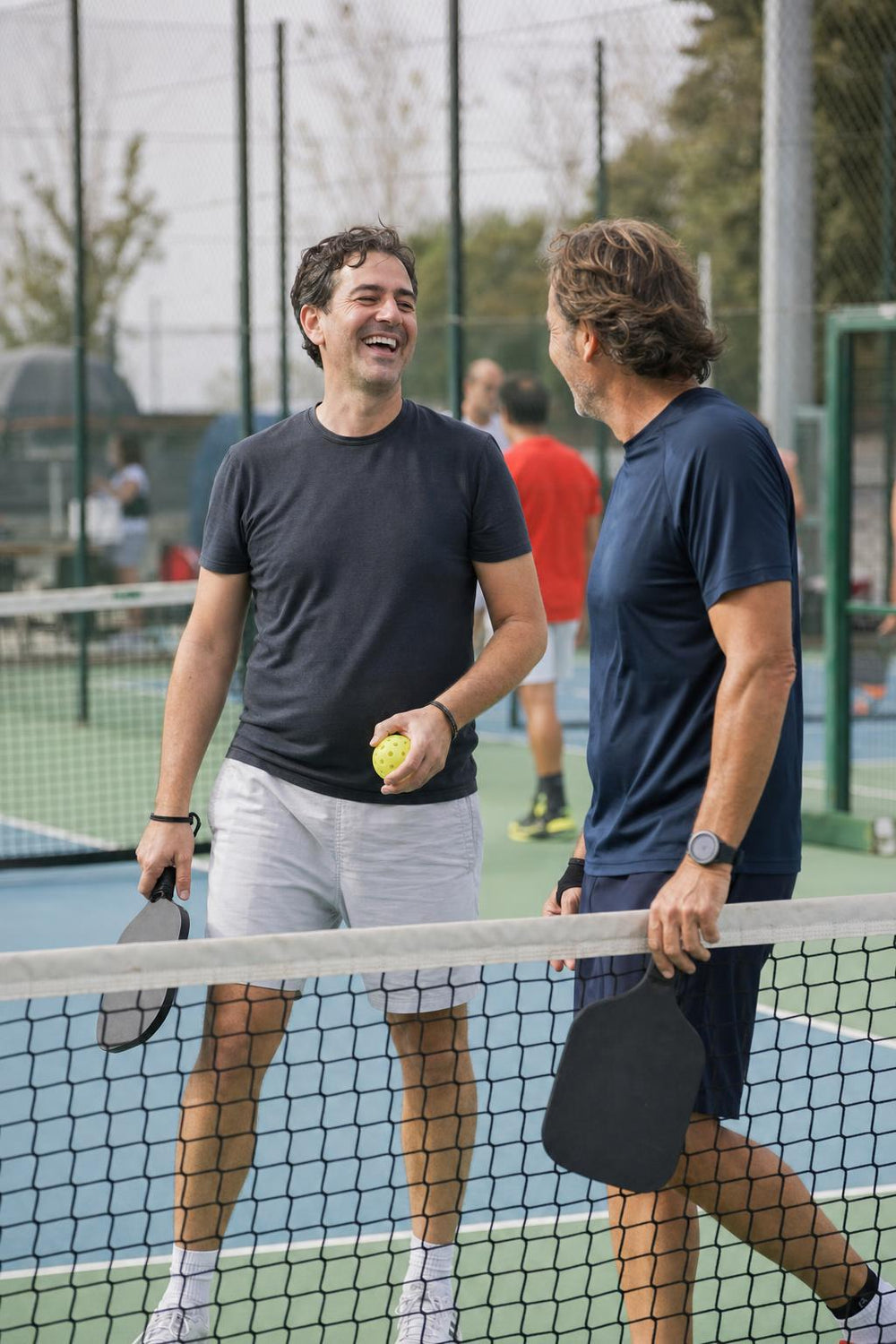 Dos jugadores de pickleball charlando en la red después de un punto