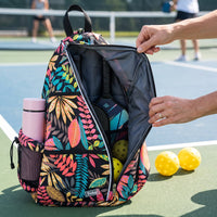 Floral-print RALLY backpack open on the court, with paddles, balls and bottle inside